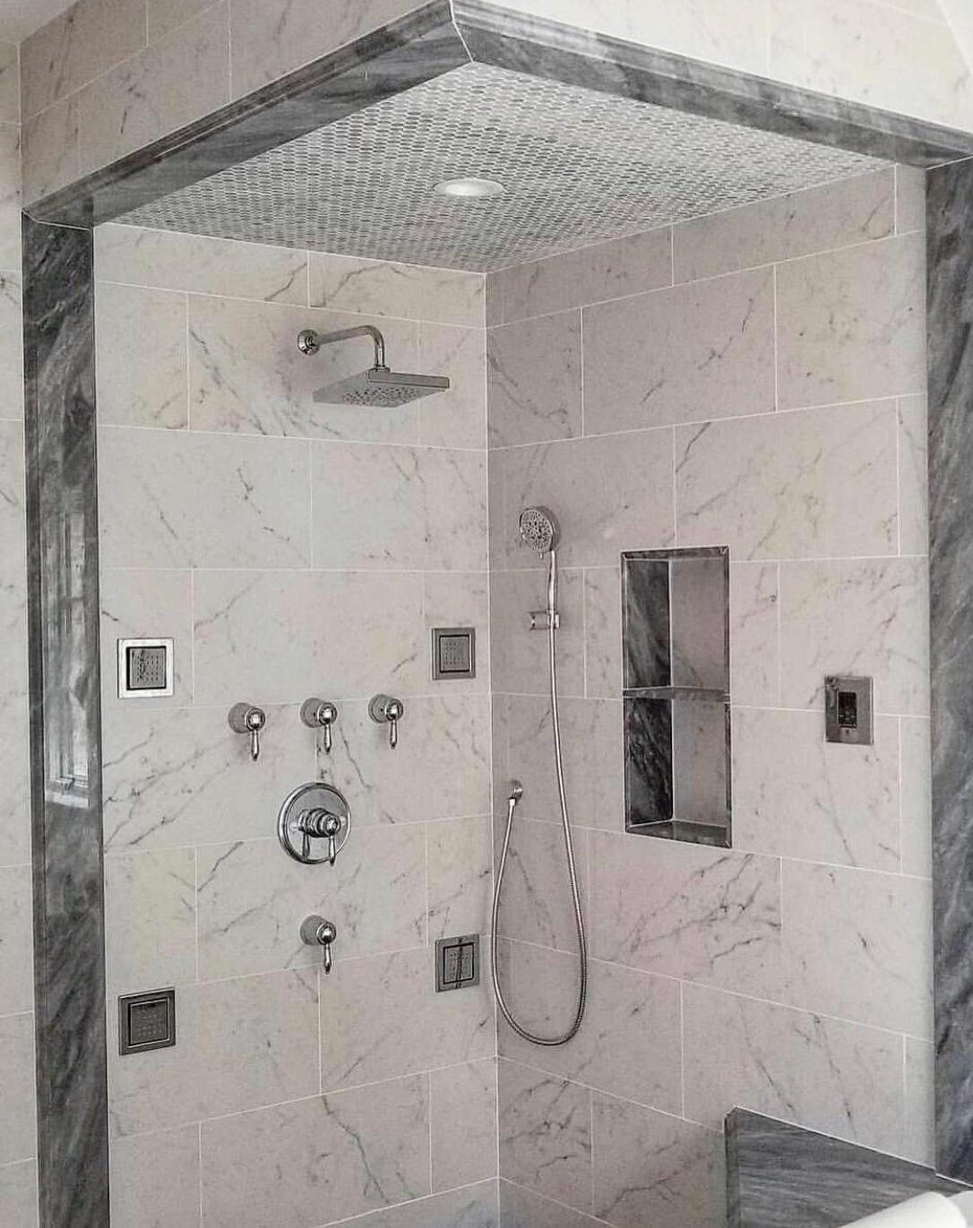 Marble-tiled shower with multiple body sprays and rainfall head